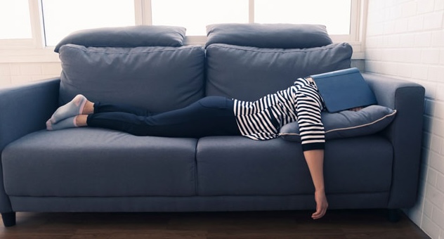 PXL_20230507_142535864 person lies facedown on sofa with an open book covering their head