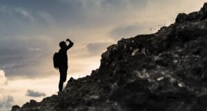 Person in profile and silhouette looking up a rocky hill