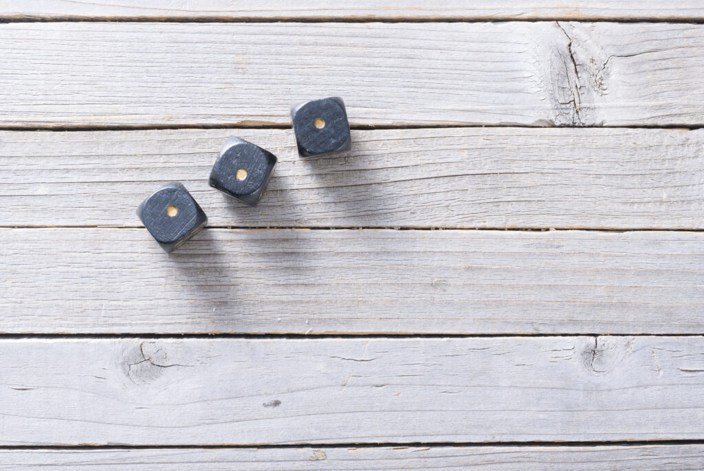 Three,Dices,With,One,Dot,On,Aged,Wooden,Background