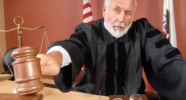 Bearded judge in black robe pounds gavel