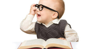 Laughing toddler wearing black-rimmed glasses and holding a book