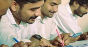 Men writing with pens or on phones, smiling