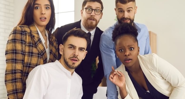 Five colleagues in a meeting, staring into the camera and looking surprised.