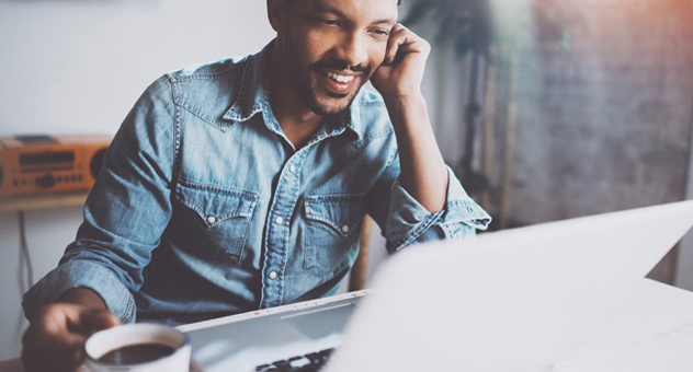 man-at-computer-with-coffee Smiling man at computer with cup of coffee