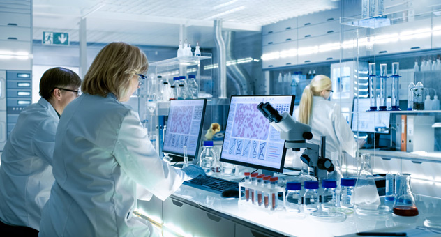 scientists-in-lab Scientists in lab coats working on computers in laboratory