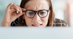 Woman in glasses, looking at screen and frowning